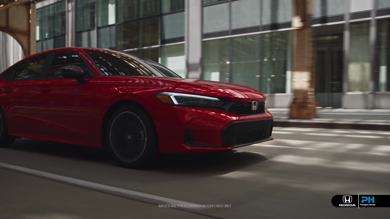 A red Honda passing a city dealership at night